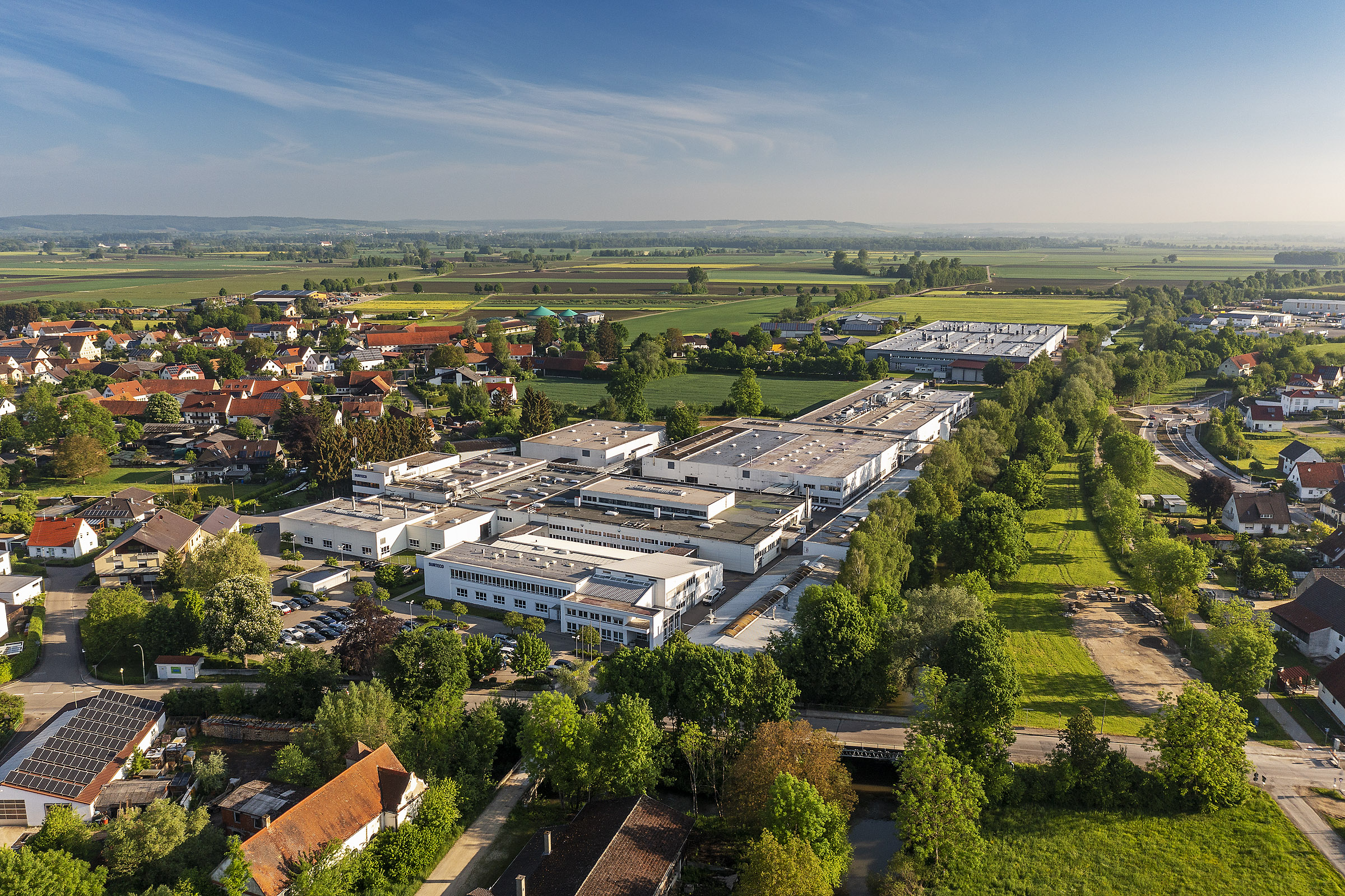 Luftaufnahme des Firmengeländes eines vor Ort ansässigen Unternehmens mit Anschluss ans Nahwärmenetz sowie PV- und Biogasanlagen im Hintergrund (Foto: Eckhart Matthäus/ www.em-foto.de).